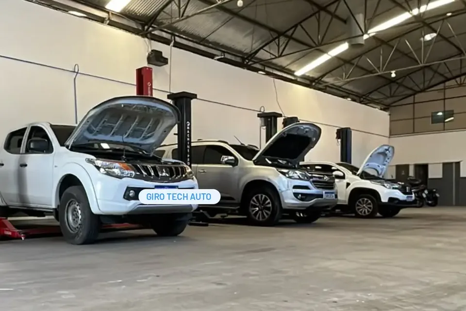 Área de serviço da GiroTech com picapes em elevadores automotivos e capôs abertos